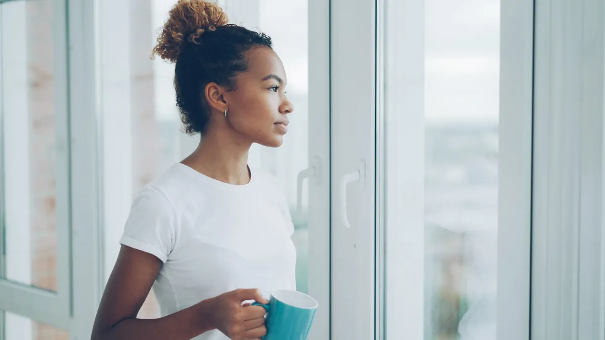 A person holding a mug beside a bright window