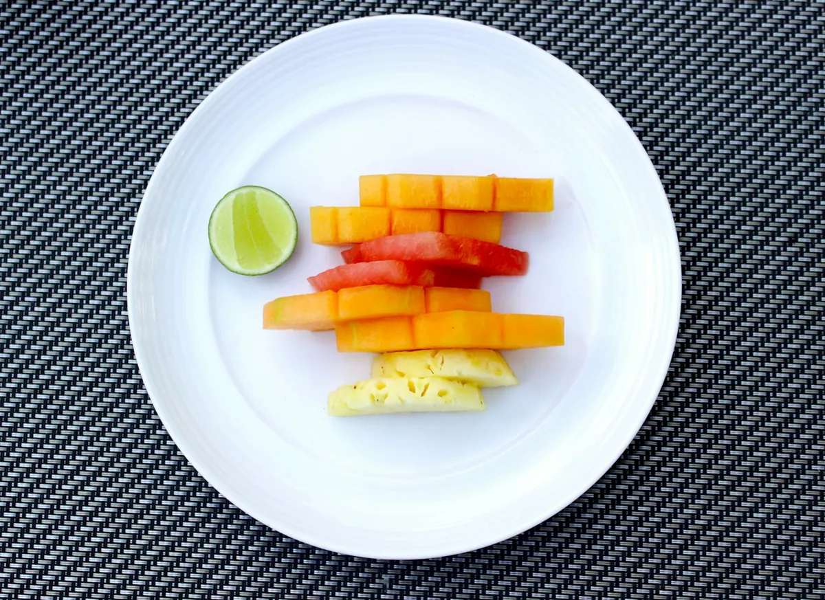 Melon and mango cut into sticks on a white plate