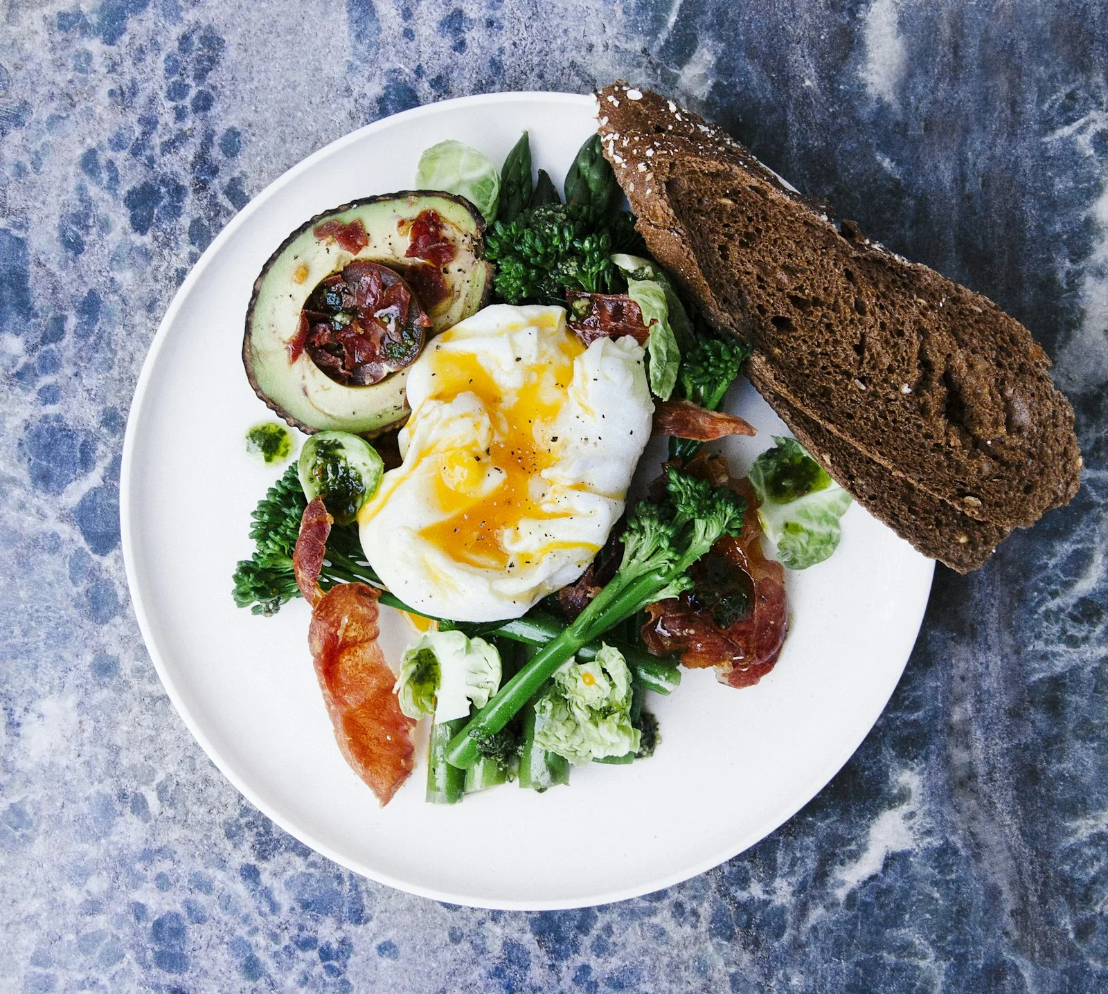 A poached egg breakfast plate with greens and rye bread