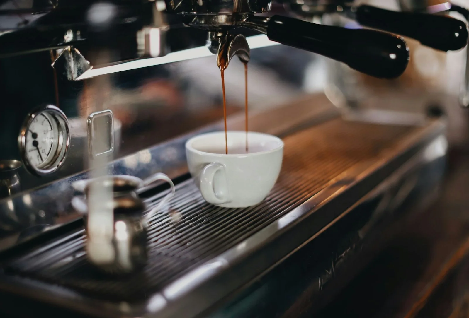 Espresso pouring from a machine into a small white cup