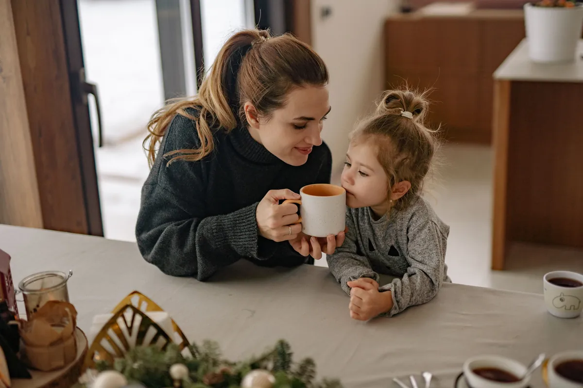 A parent and toddler sitting together holding mugs
