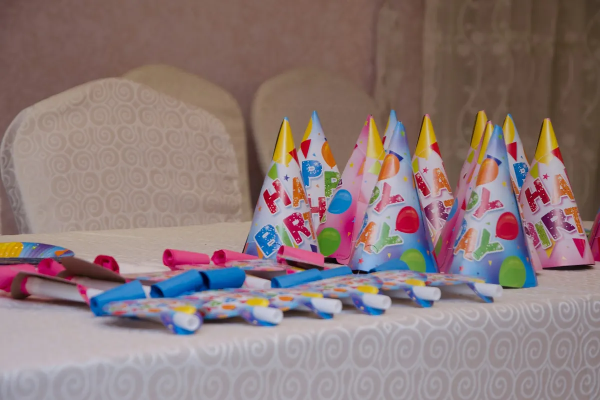 Party hats and small treats laid out along a party table