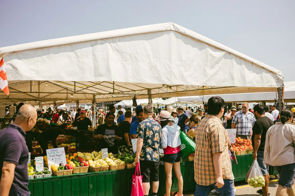 People browsing produce under a covered market awning