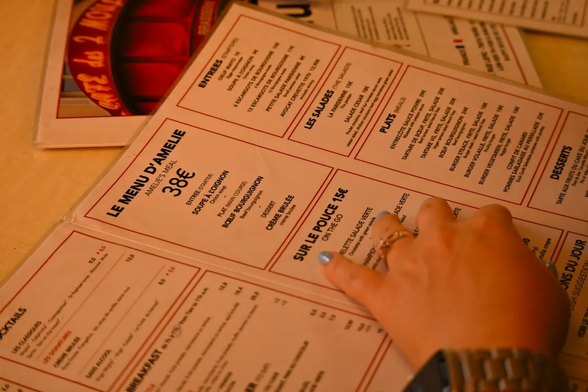 A hand holding a printed menu at a restaurant table