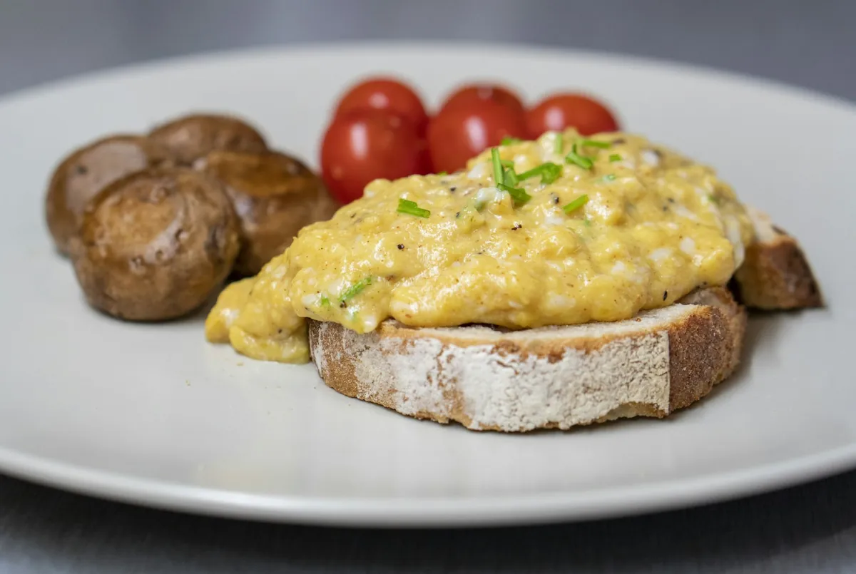 Scrambled egg on toast served with tomatoes and mushrooms