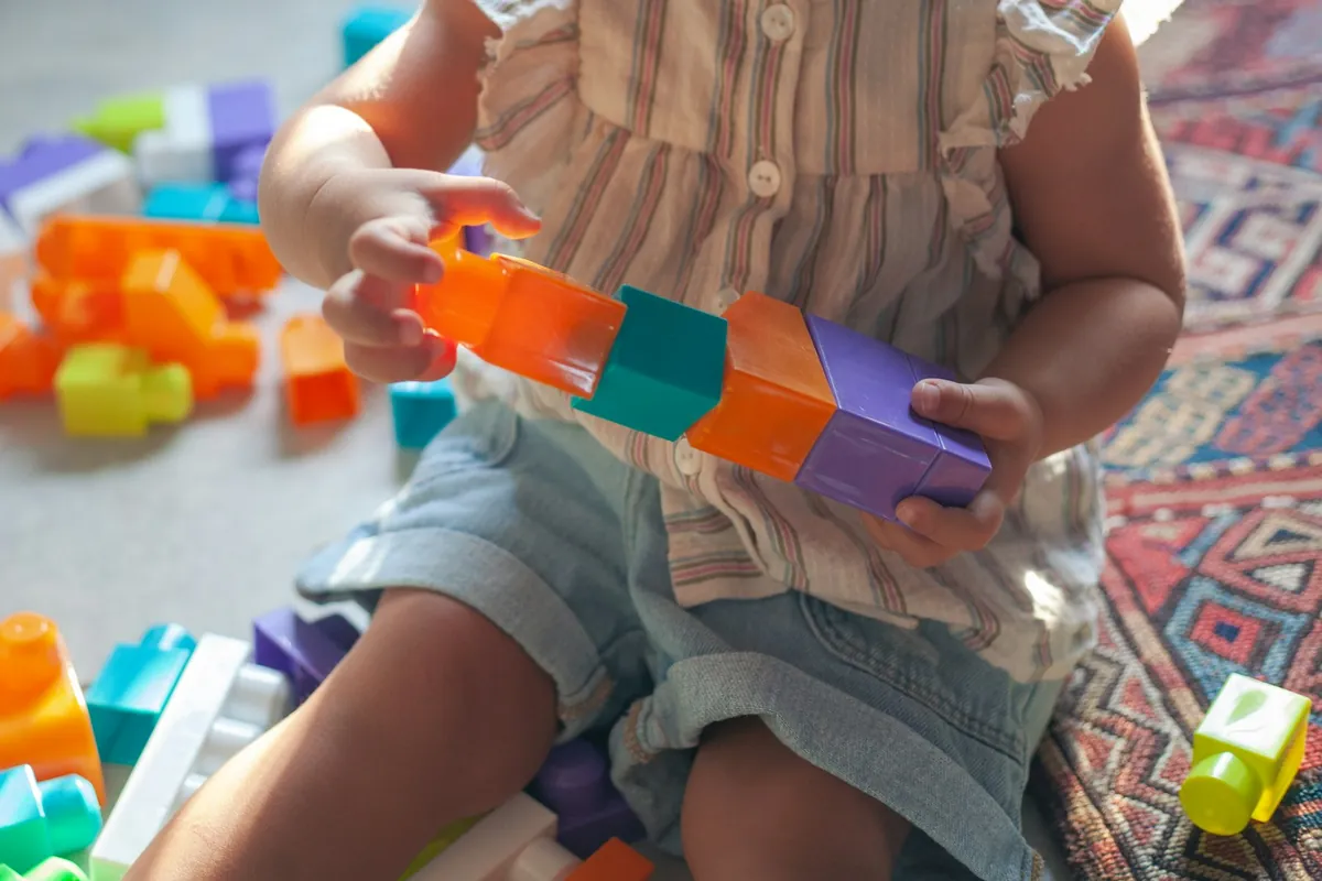 Small hands stacking brightly coloured plastic blocks