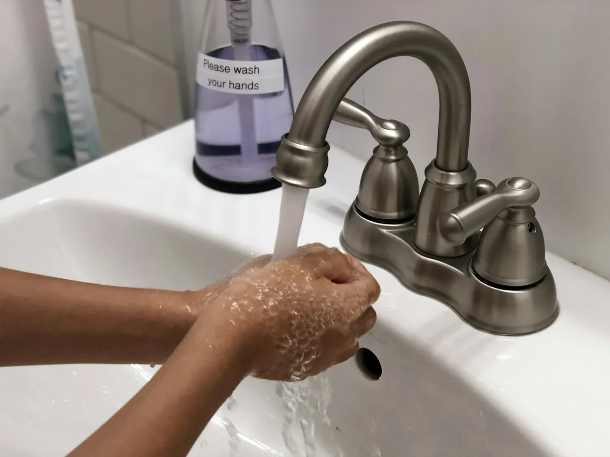 Small hands being washed with soap at a sink