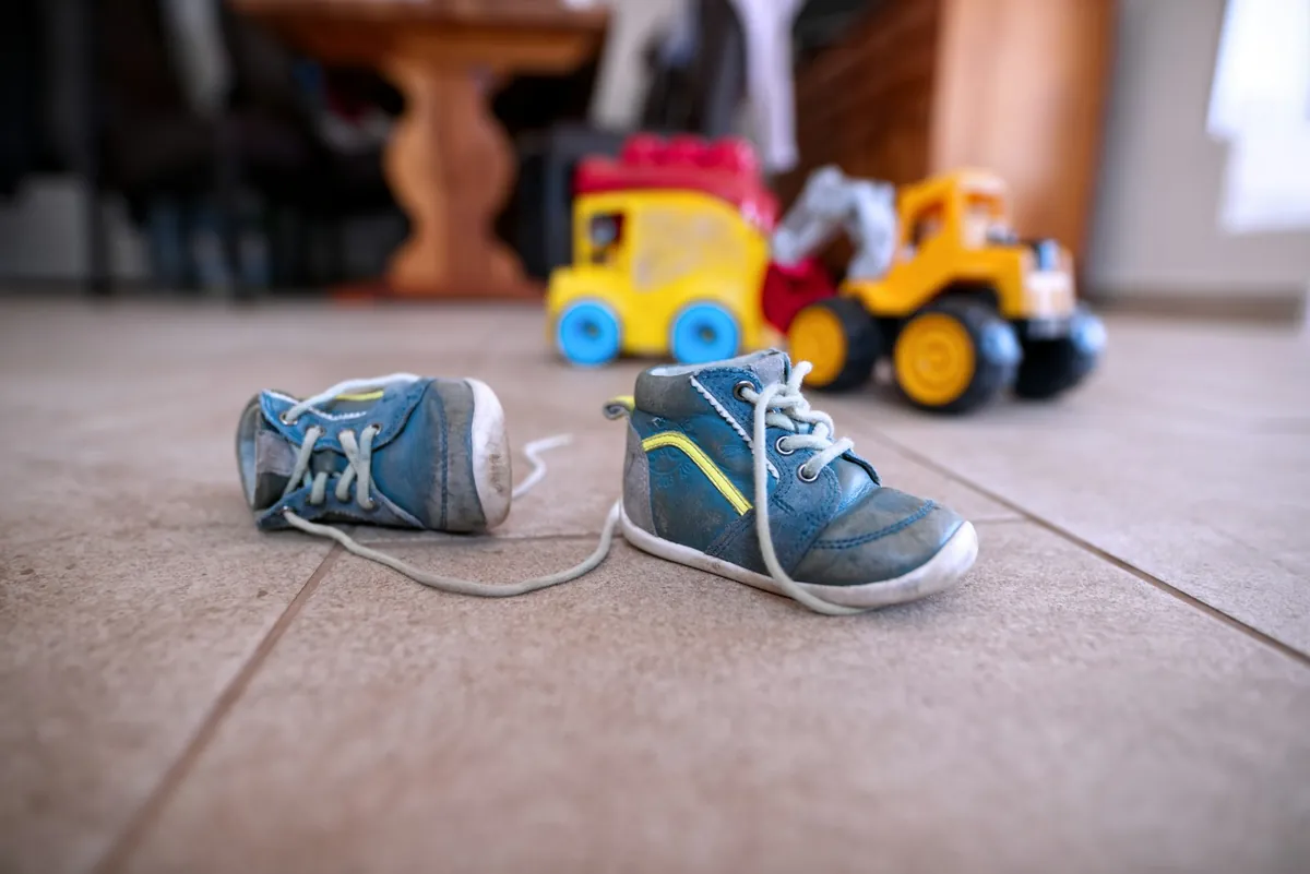 A pair of small shoes and toy cars on a floor