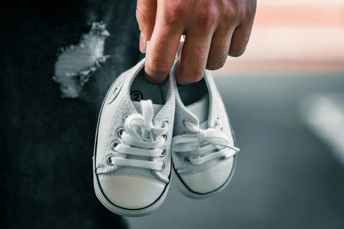 A pair of small white shoes held up