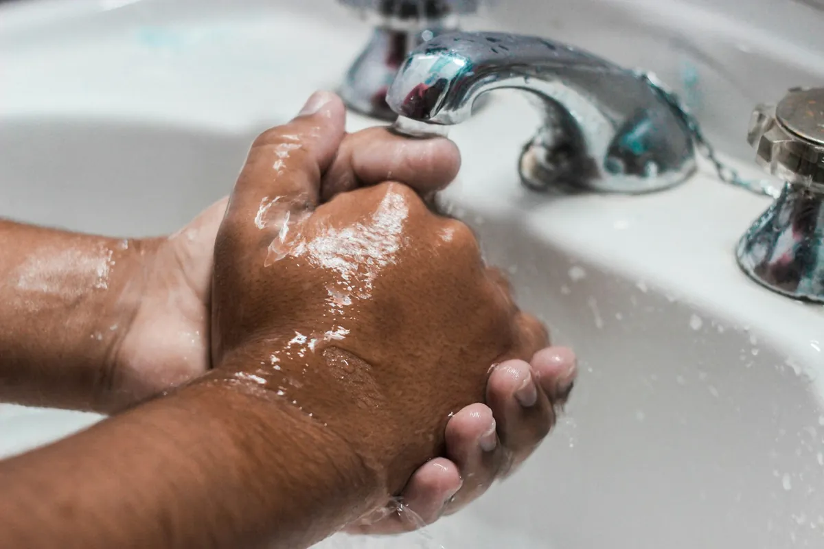 Soapy hands being rinsed under a running tap