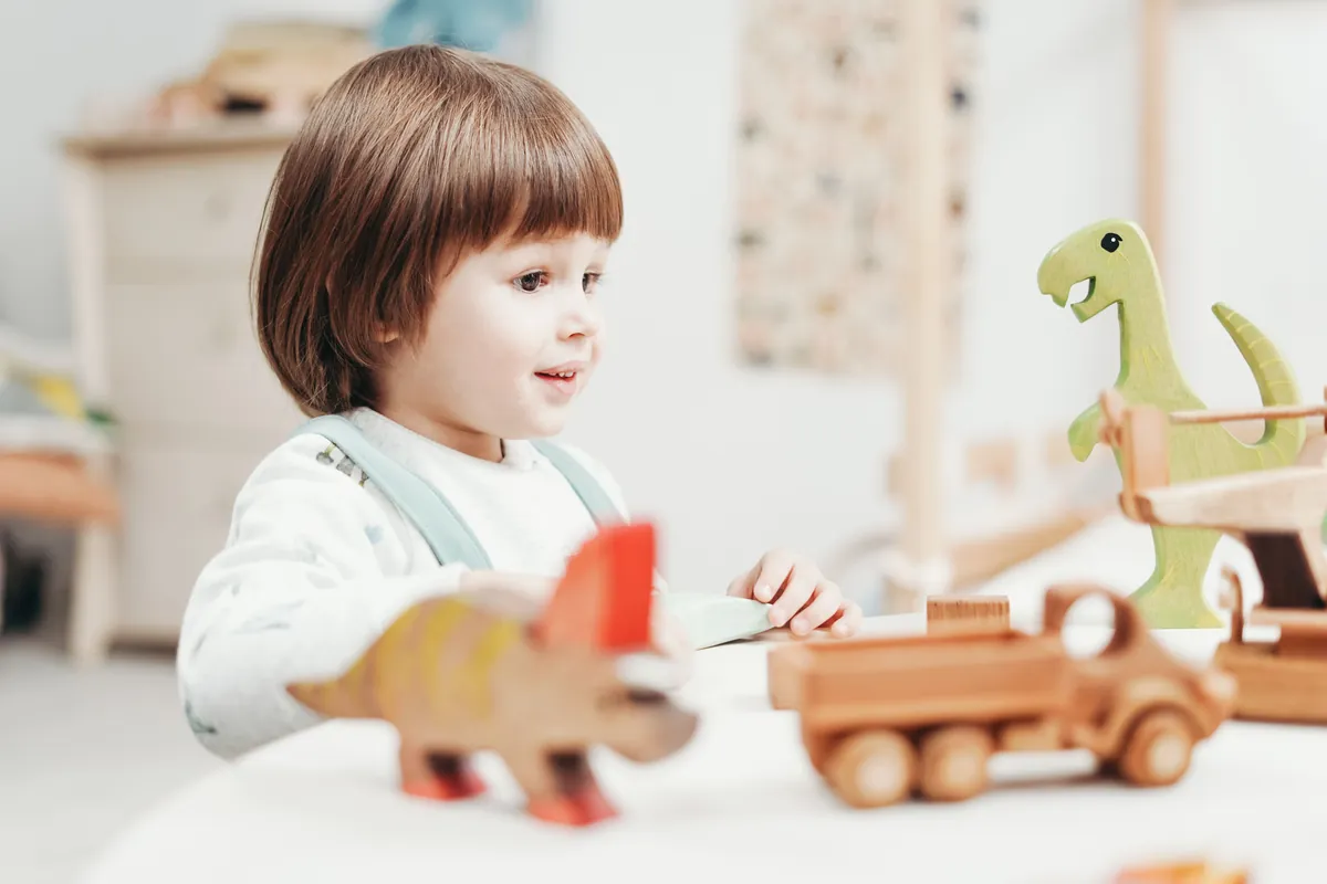 A toddler playing with wooden animal toys at a low table