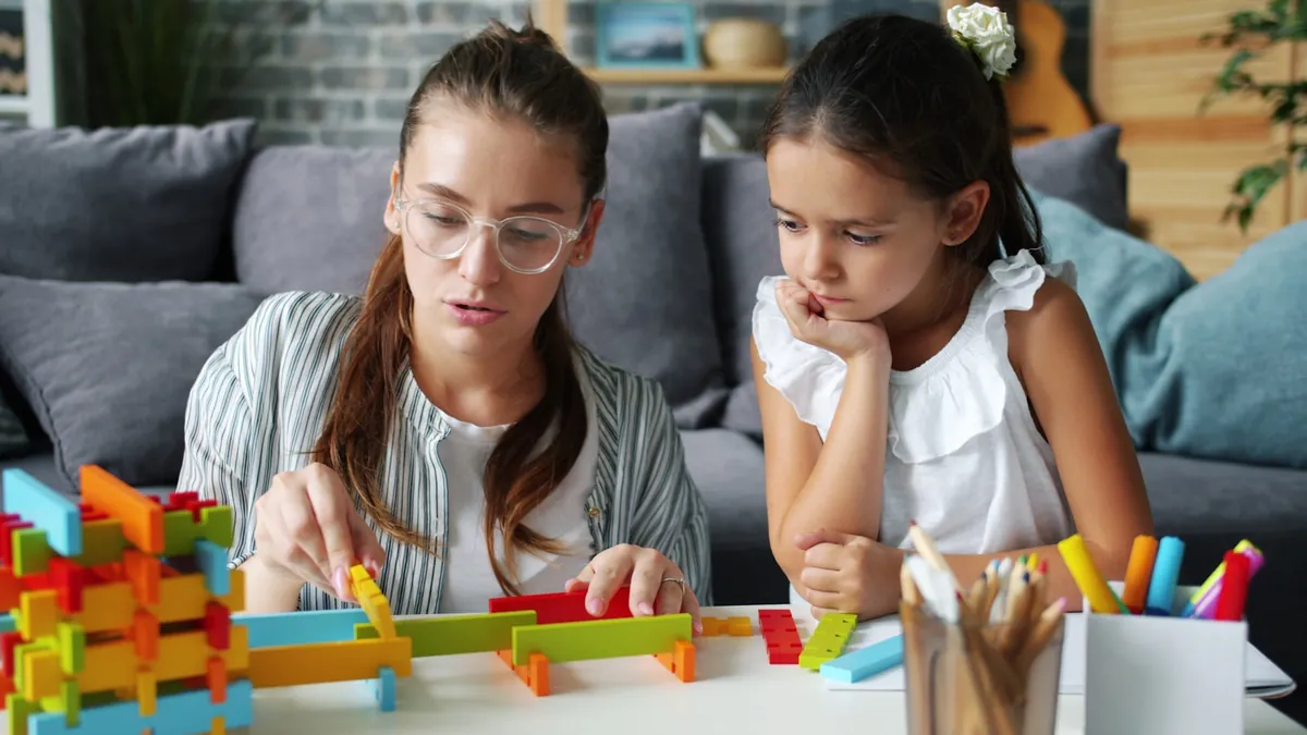 Two children building with coloured blocks on a rug