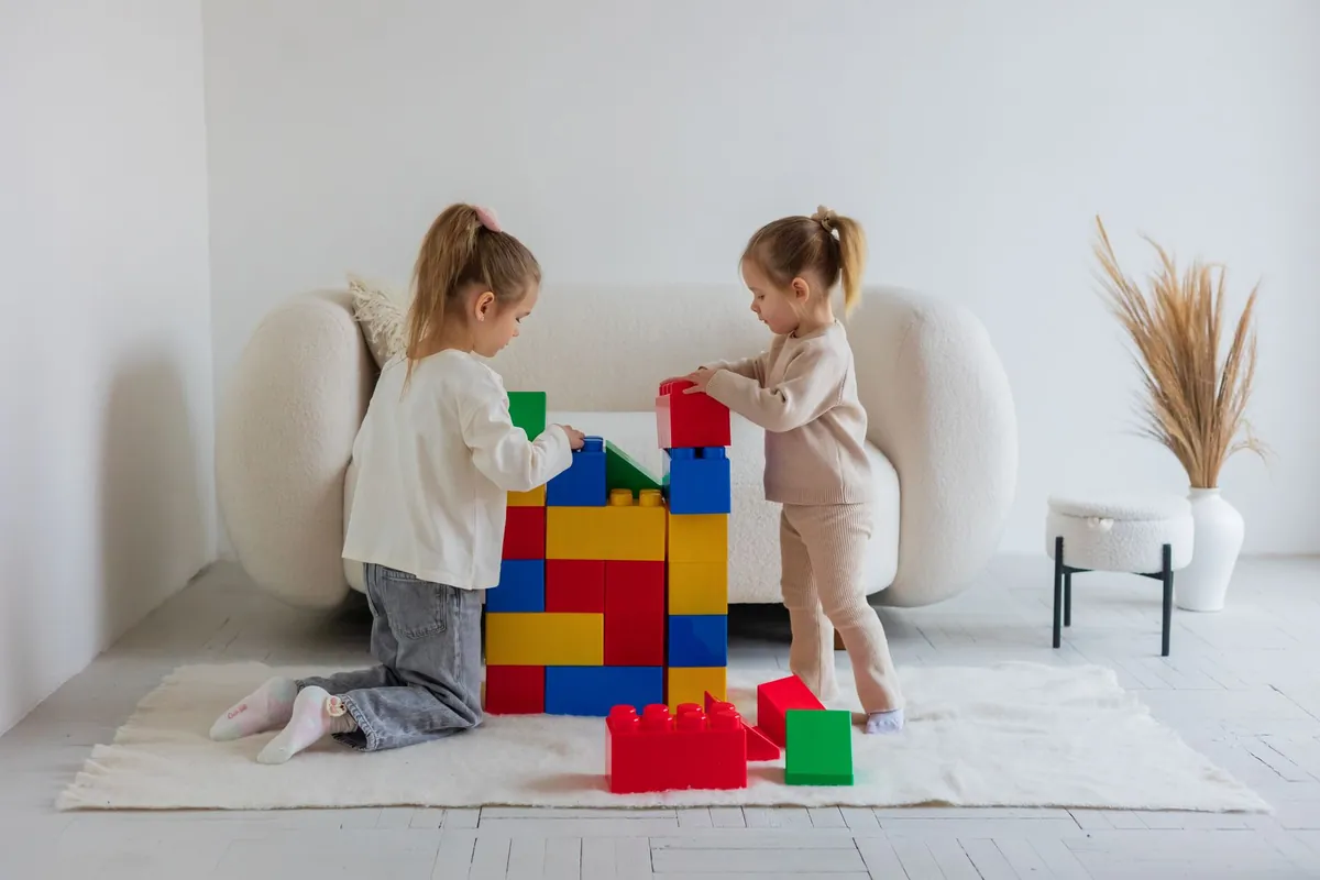 Two young children building a tower from coloured blocks