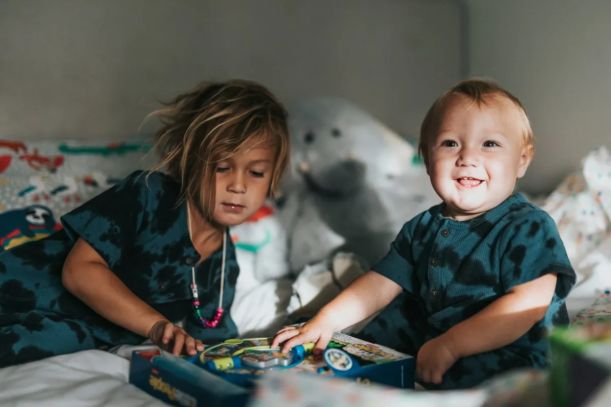 Two children playing together on a bed