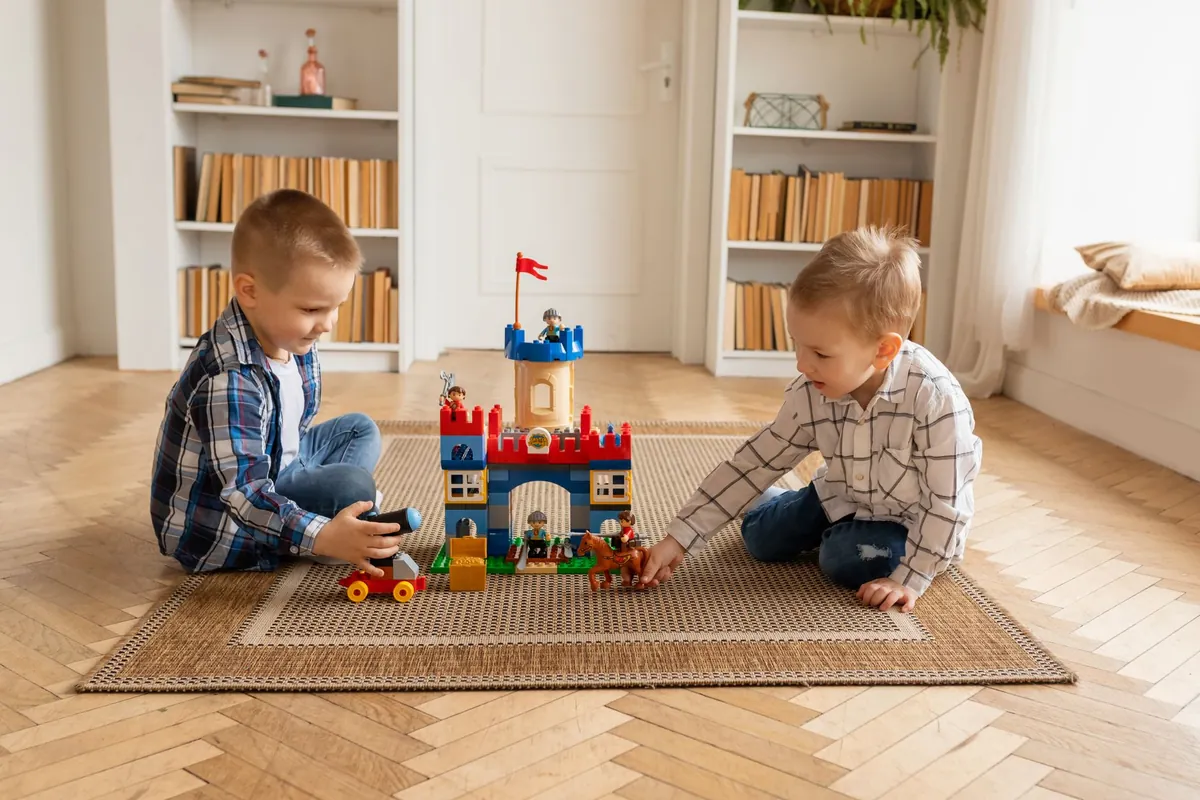 Two children playing with building blocks on a rug