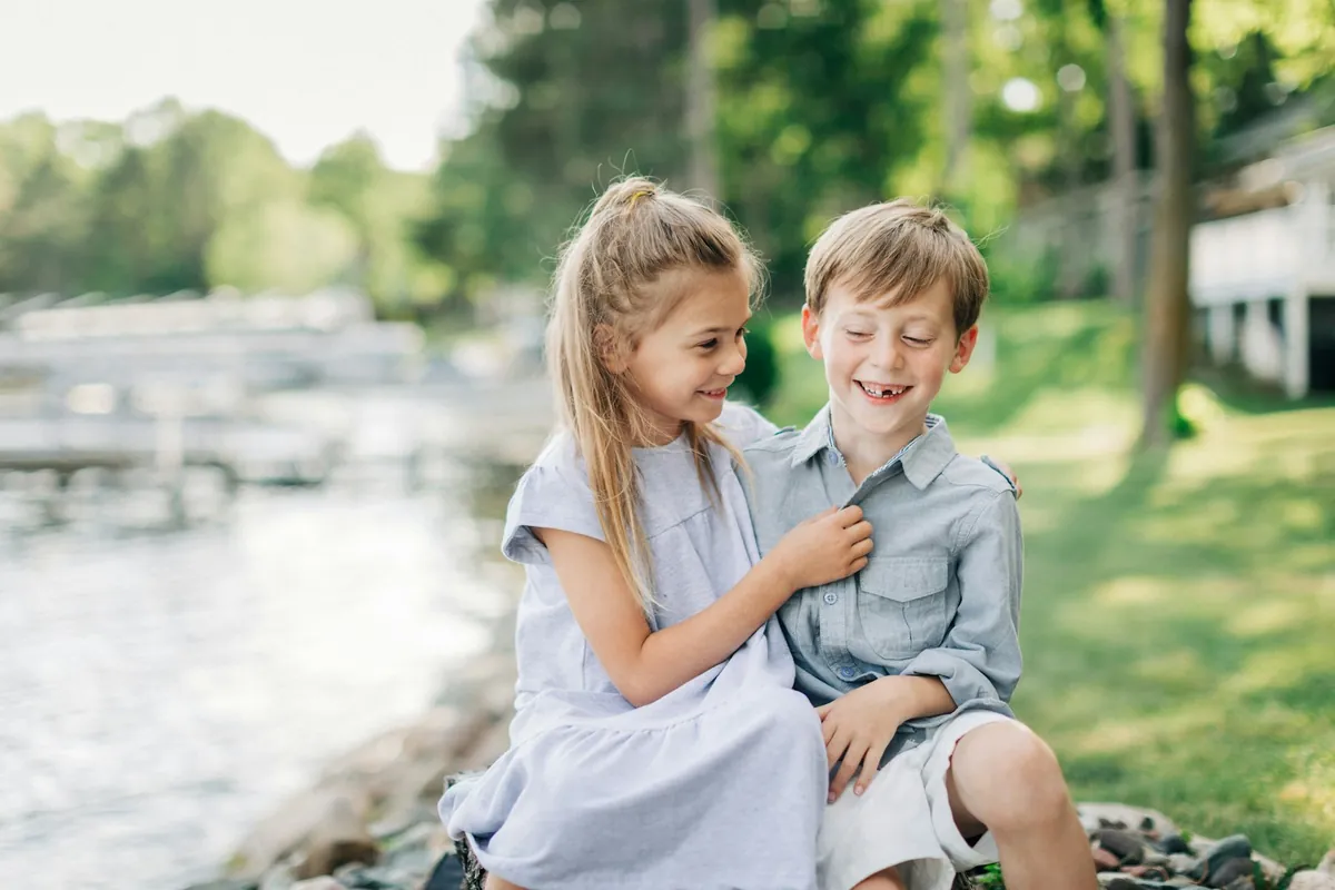 Two young children sitting together on a step outdoors