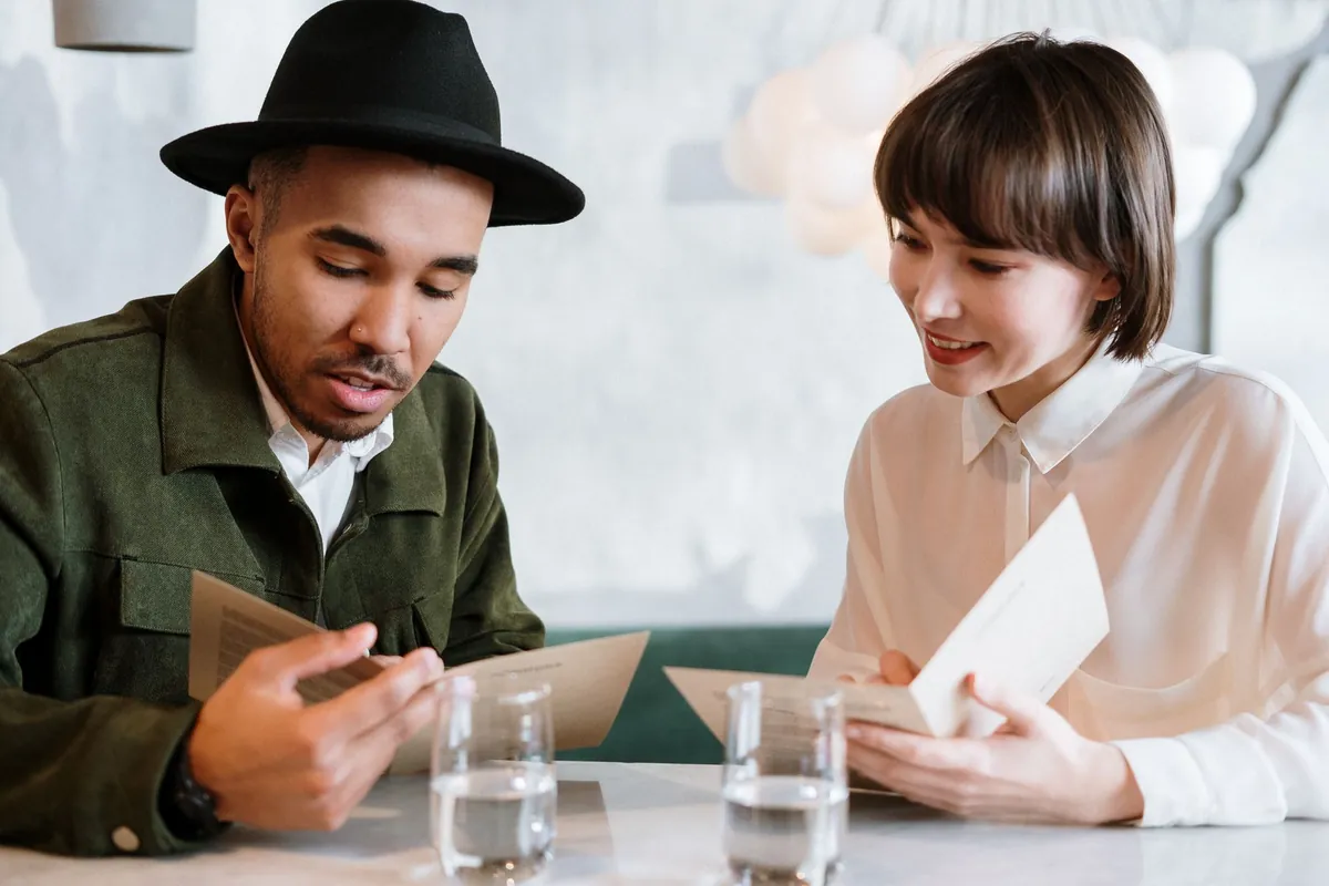 Two people reading menus together at a cafe table