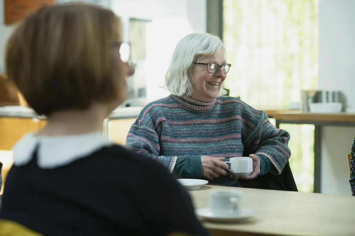 Two people talking over cups of coffee at a table