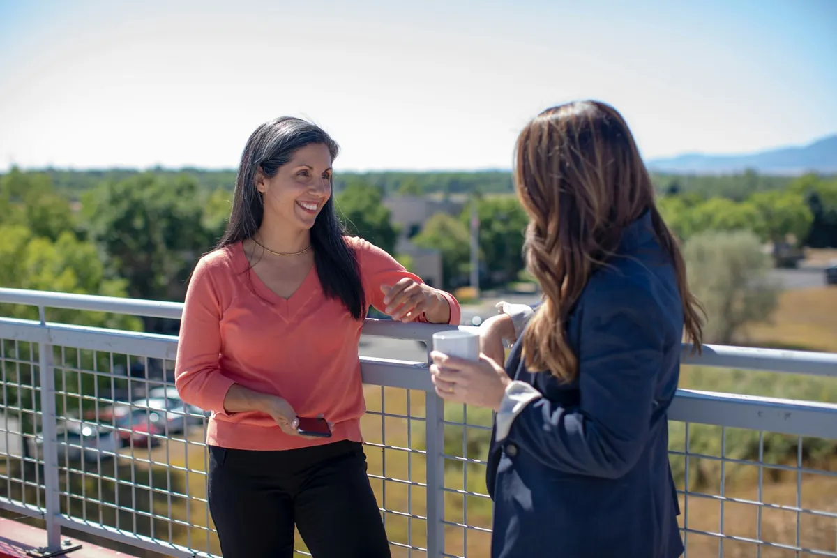 Two people talking with drinks in hand outdoors