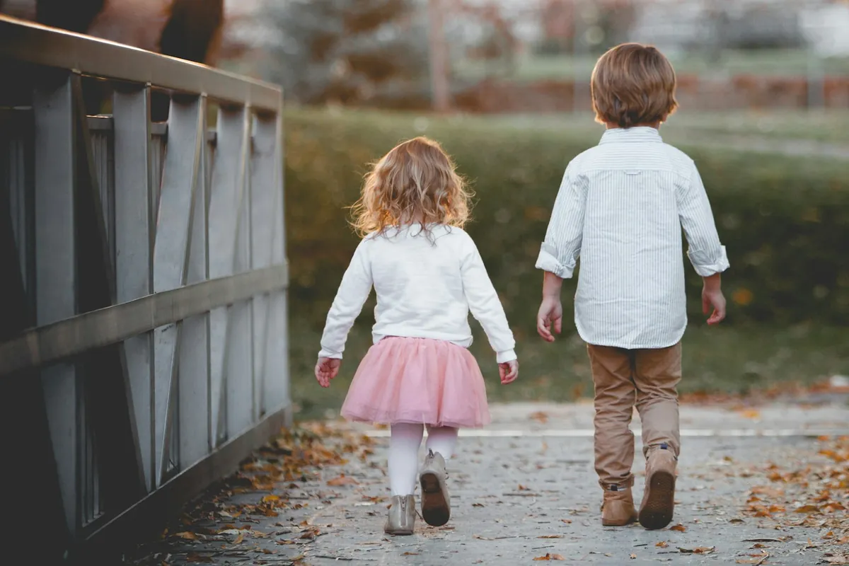 Two young children walking along together outdoors