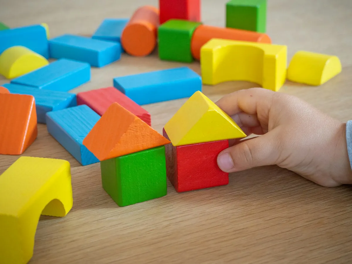 Coloured wooden blocks on a floor with a child hand