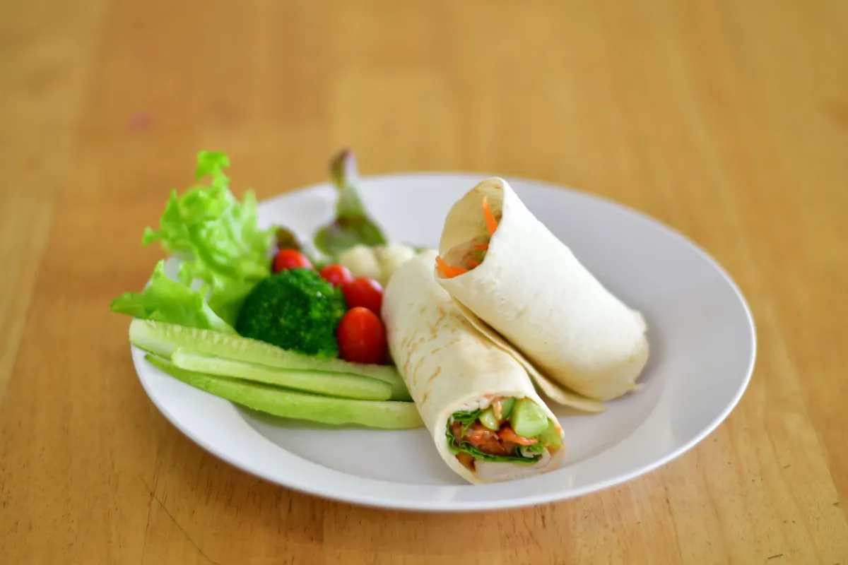 Wraps served with salad and cucumber on a white plate